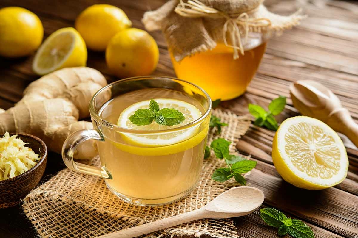 Boisson chaude avec tranche de citron, citrons et gingembre posés sur une table