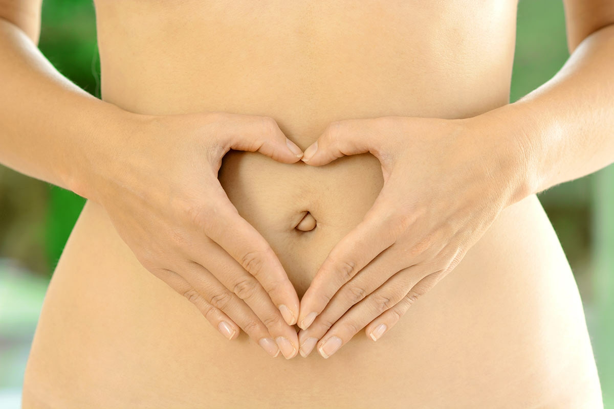 Deux mains de femme forment un coeur sur son ventre