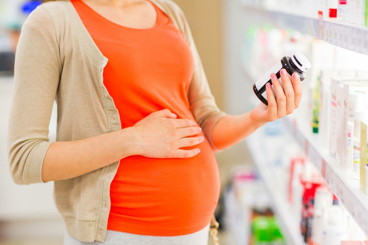 Femme enceinte achetant ses vitamines de grossesse en pharmacie