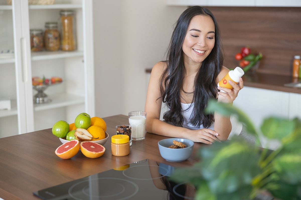 Femme souriante prenant un petit déjeuner équilibré et des vitamines anti-dépression