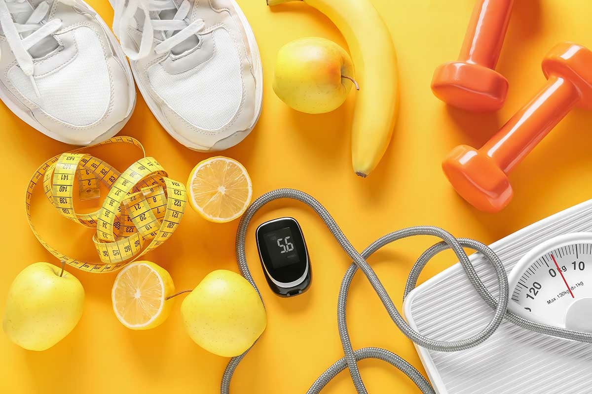 Fruits, haltères, baskets, pèse personne, mètre ruban sur un fond jaune
