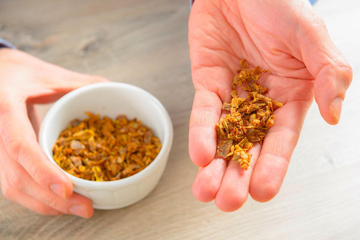 Main prenant de la propolis brute dans un bol, pour l’utiliser à mâcher