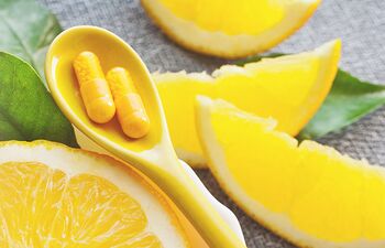 Orange et comprimés vitamine C dans une cuillère jaune