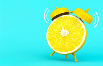 Réveil matin en forme d’orange sur fond turquoise